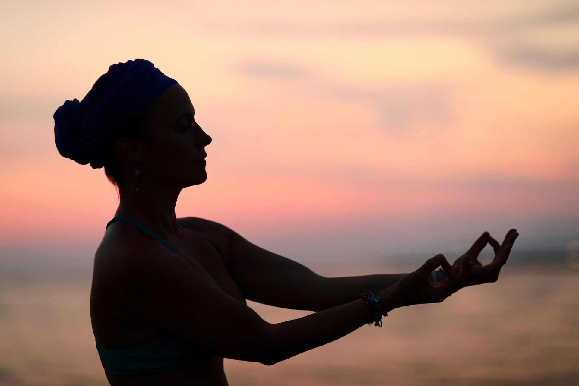 Woman practise yoga kundalini on sandy beach in sunset.